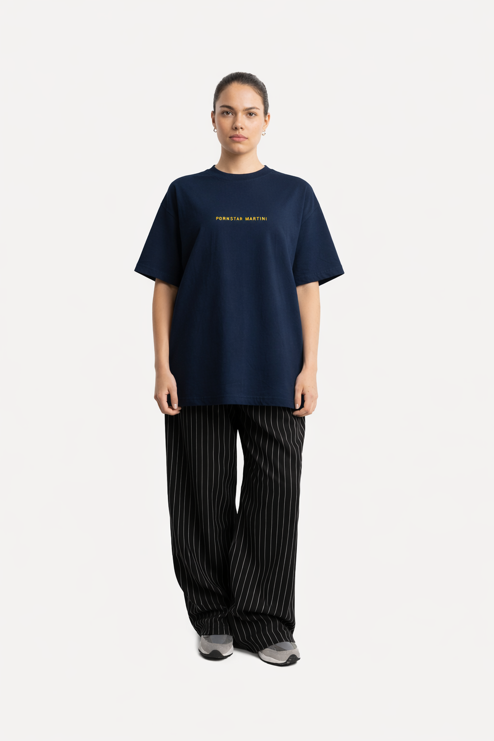 Person wearing a navy blue t-shirt with text and black striped pants on a white background