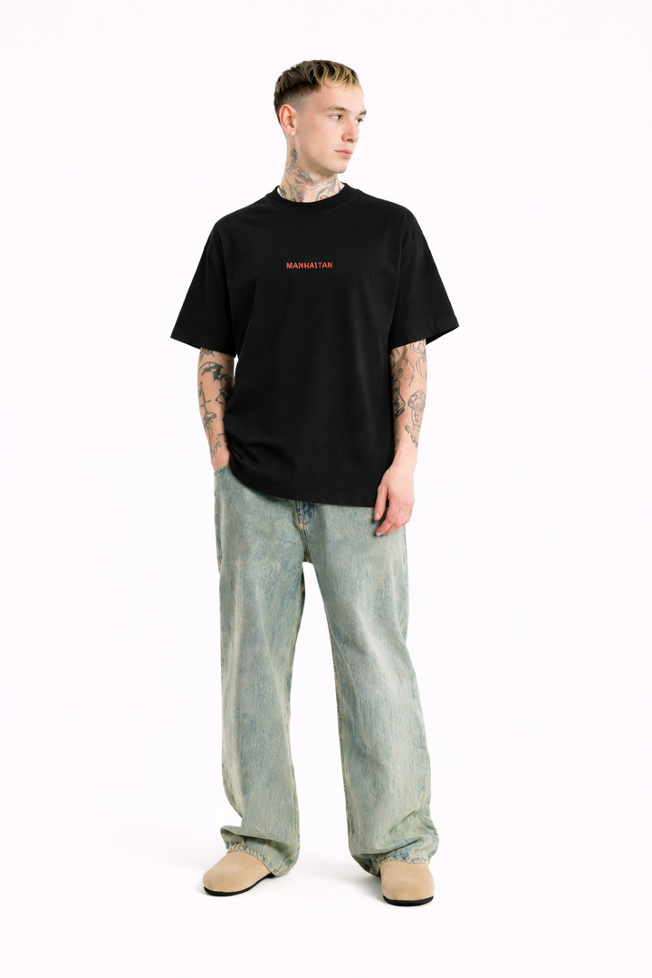 Person wearing a black t-shirt with red text and light blue jeans on a white background