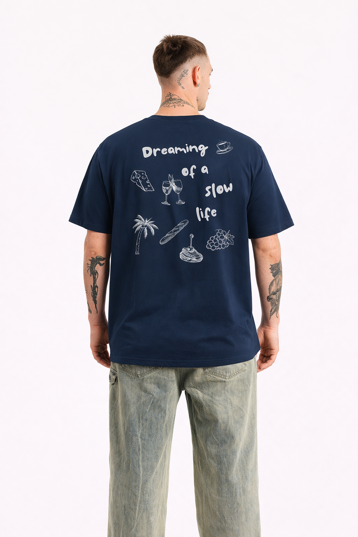 Man wearing a navy blue t-shirt with graphics and text on the back, standing against a white background.