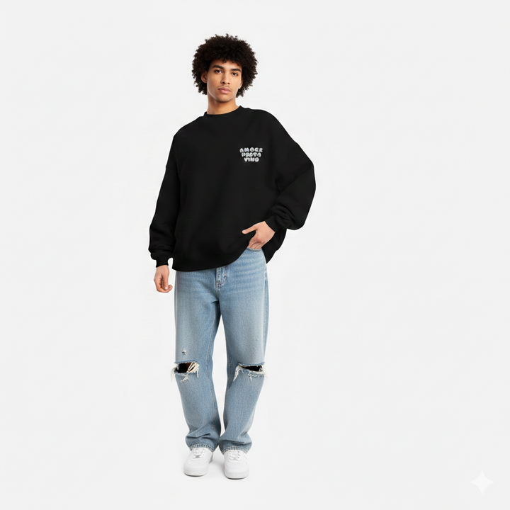 Person wearing a black sweatshirt and light blue jeans on a white background