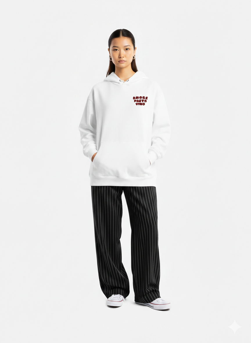 Person wearing a white hoodie with text and black pinstripe pants on a white background