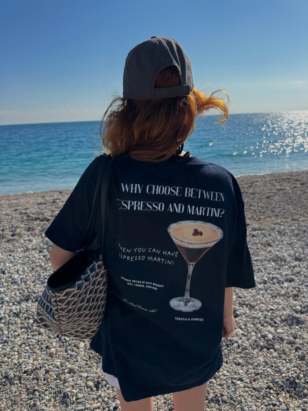Espresso Martini Organic T-shirt worn by a person at the beach, featuring a cocktail graphic and playful text.