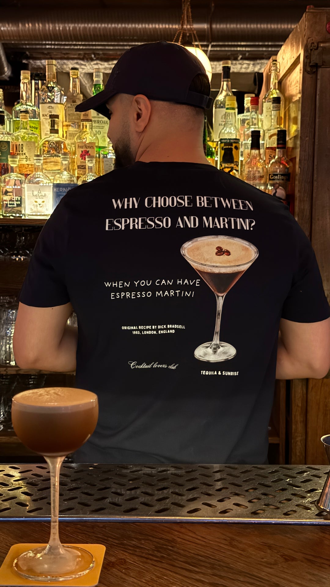 Espresso Martini Organic T-shirt design featuring cocktail and text, worn by a person in a bar setting.