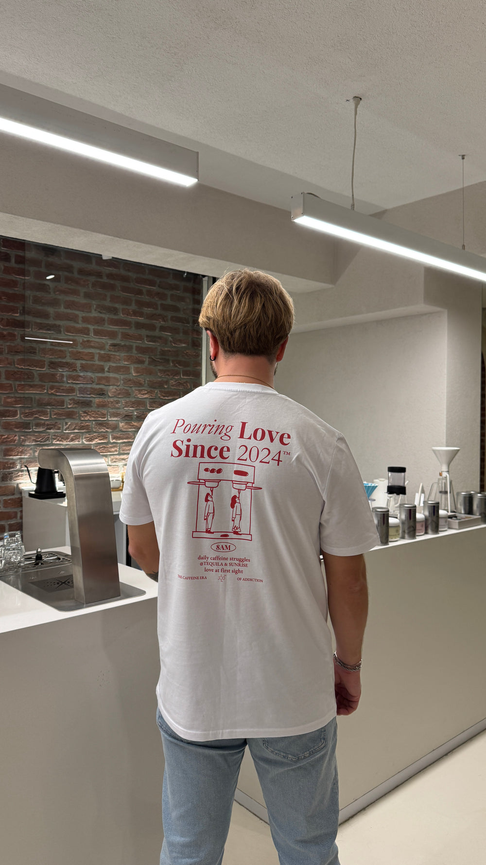 Person wearing a white t-shirt with the phrase 'Pouring Love Since 2024' displayed on the back.