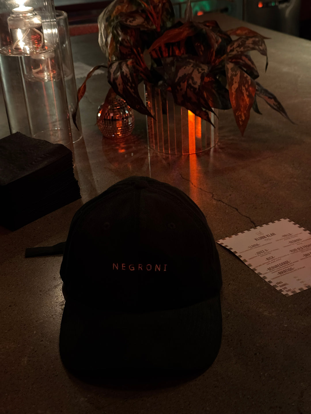 Black bag with 'Nevron' branding on a table with a plant and glassware in the background.