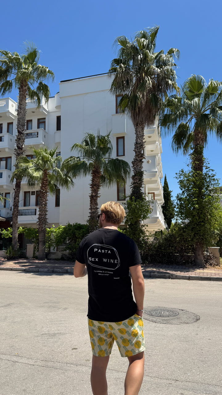 Man wearing Pasta & Sex & Wine Organic T-shirt in a sunny location with palm trees.