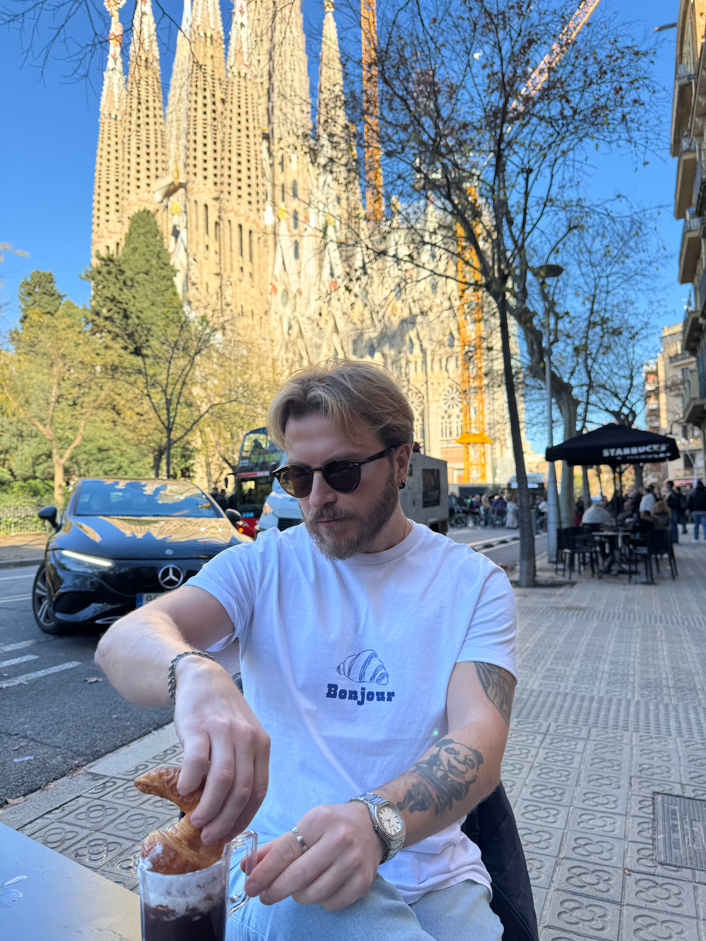 Man eating a pastry with a cathedral in the background