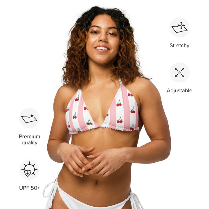 Model wearing a cherry string bikini top, displaying the bikini's features, styled for a summer beach look."