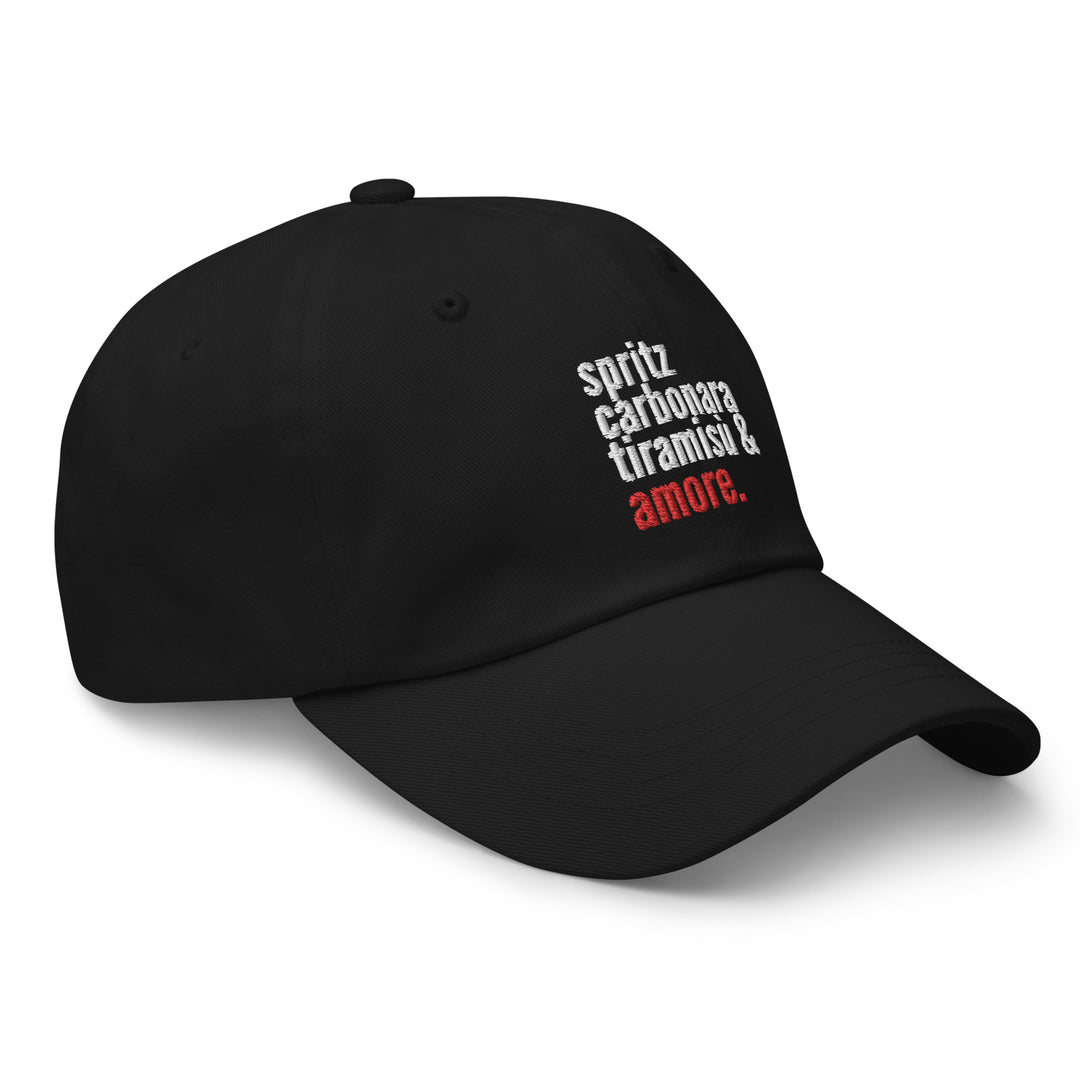 The Love from Italy Hat by Tequila & Sunrise is a black dad hat made from durable chino cotton twill. It features white and red text that reads "spritz carbonara tiramisù & amore" and includes an adjustable strap for a perfect fit.