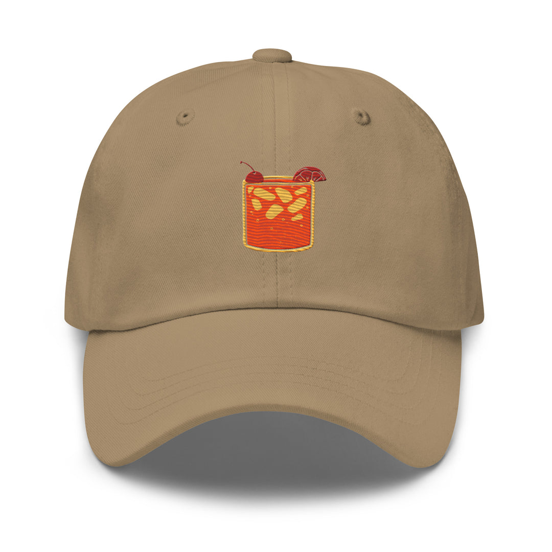 Introducing the Tequila & Sunrise Glass Hat by Tequila & Sunrise – a khaki dad hat with a low-profile design, featuring an embroidered orange drink complete with a straw and an orange slice. It comes with an adjustable strap to ensure the perfect fit.