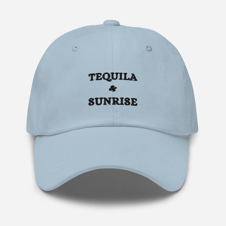 The Tequila & Sunrise Hat by Tequila & Sunrise is a light blue dad hat with the brand's logo embroidered in black on the front and features an adjustable strap for a comfortable fit.