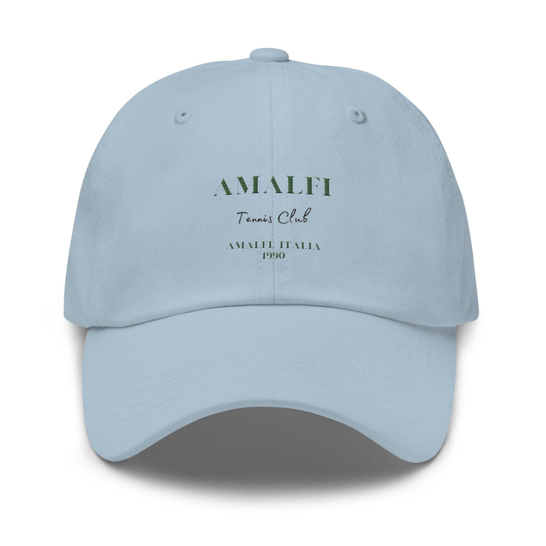 Introducing The Amalfi Tennis Club Italia Hat by Tequila & Sunrise, a light blue dad hat made from chino cotton twill. It includes an adjustable strap for a customized fit, with "AMALFI Tennis Club" and "AMALFI ITALIA 1990" boldly printed on the front, evoking a blend of timeless style and vintage charm.