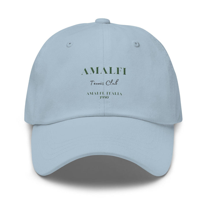 Introducing The Amalfi Tennis Club Italia Hat by Tequila & Sunrise, a light blue dad hat made from chino cotton twill. It includes an adjustable strap for a customized fit, with "AMALFI Tennis Club" and "AMALFI ITALIA 1990" boldly printed on the front, evoking a blend of timeless style and vintage charm.