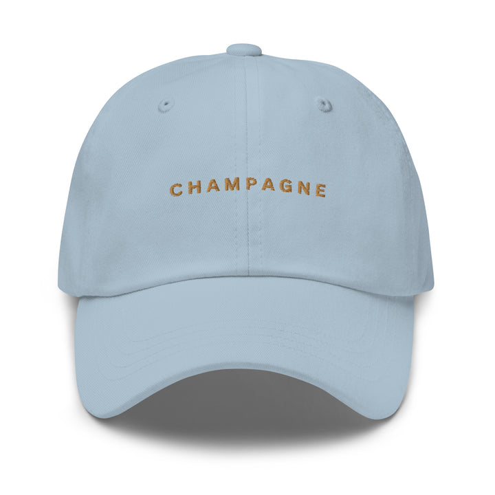 The Champagne Dad Hat by Tequila & Sunrise is crafted from light blue chino cotton twill and features the word CHAMPAGNE embroidered in gold on the front. This dad hat includes an adjustable strap for a customized fit.