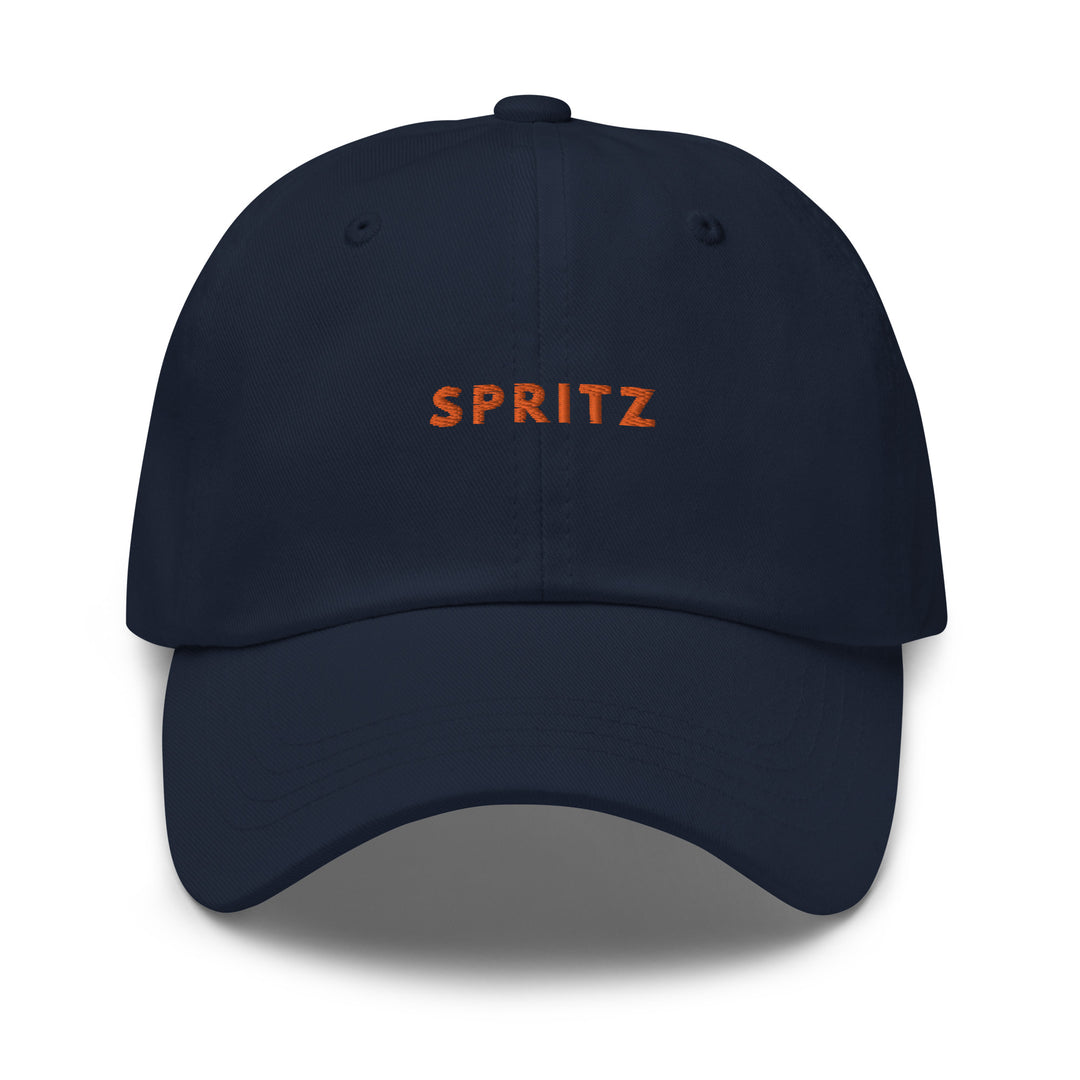 The Spritz Dad hat by Tequila & Sunrise is a low profile, navy blue cap showcasing the word SPRITZ prominently in bold orange on the front. It includes an adjustable strap to ensure a perfect fit.