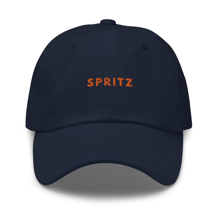 The Spritz Dad hat by Tequila & Sunrise is a low profile, navy blue cap showcasing the word SPRITZ prominently in bold orange on the front. It includes an adjustable strap to ensure a perfect fit.