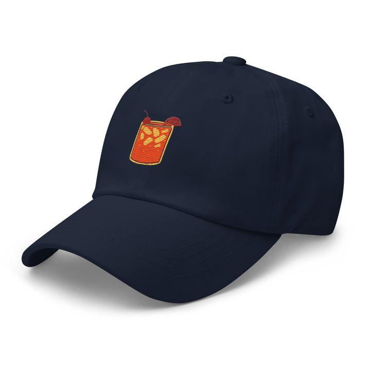 The Tequila & Sunrise Glass Hat by Tequila & Sunrise is a navy blue Dad hat featuring an embroidered cocktail glass filled with a red drink and orange slices, complete with an adjustable strap for the perfect fit.