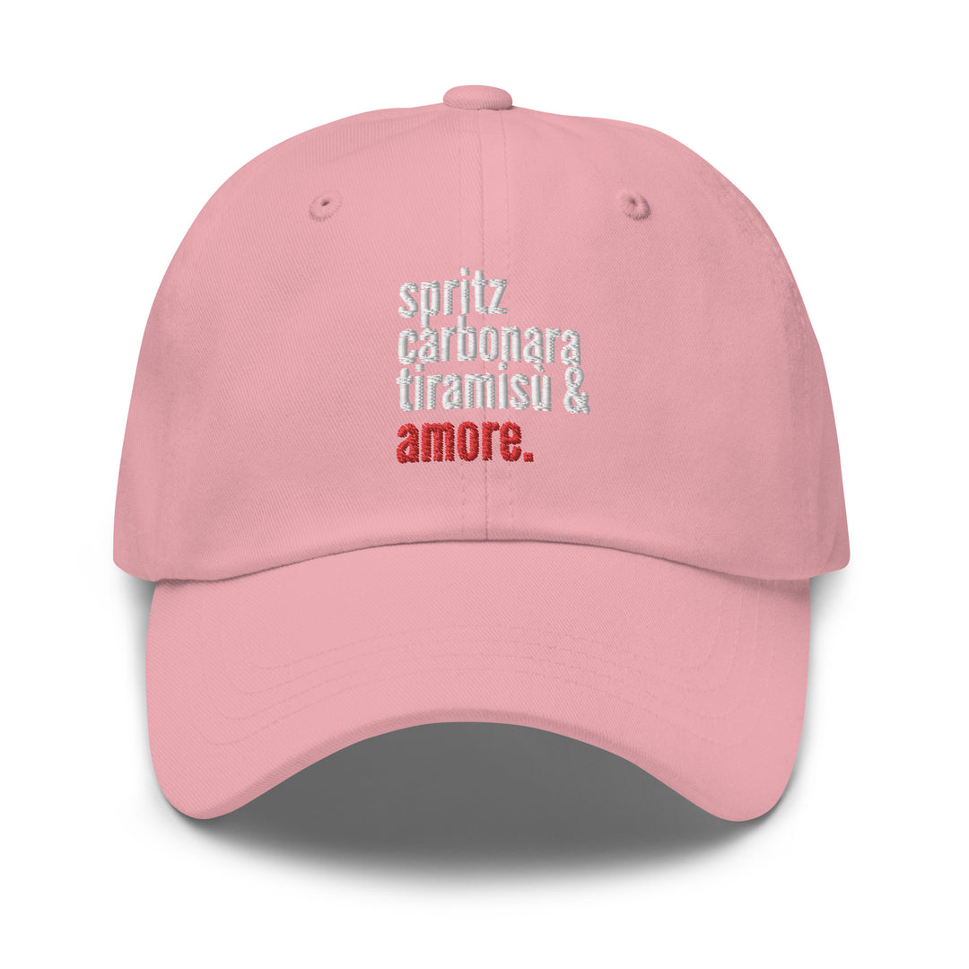 The Love from Italy Hat by Tequila & Sunrise is a pink dad hat made from chino cotton twill, showcasing white and red text that reads: spritz carbonara tiramisu & amore. It includes an adjustable strap for the perfect fit.