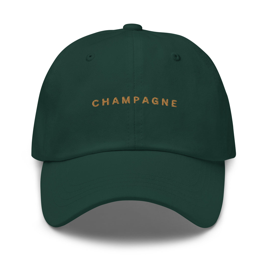 The Champagne Dad Hat by Tequila & Sunrise is a green baseball cap made from chino cotton twill, featuring gold "CHAMPAGNE" text on the front and an adjustable strap for a perfect fit.