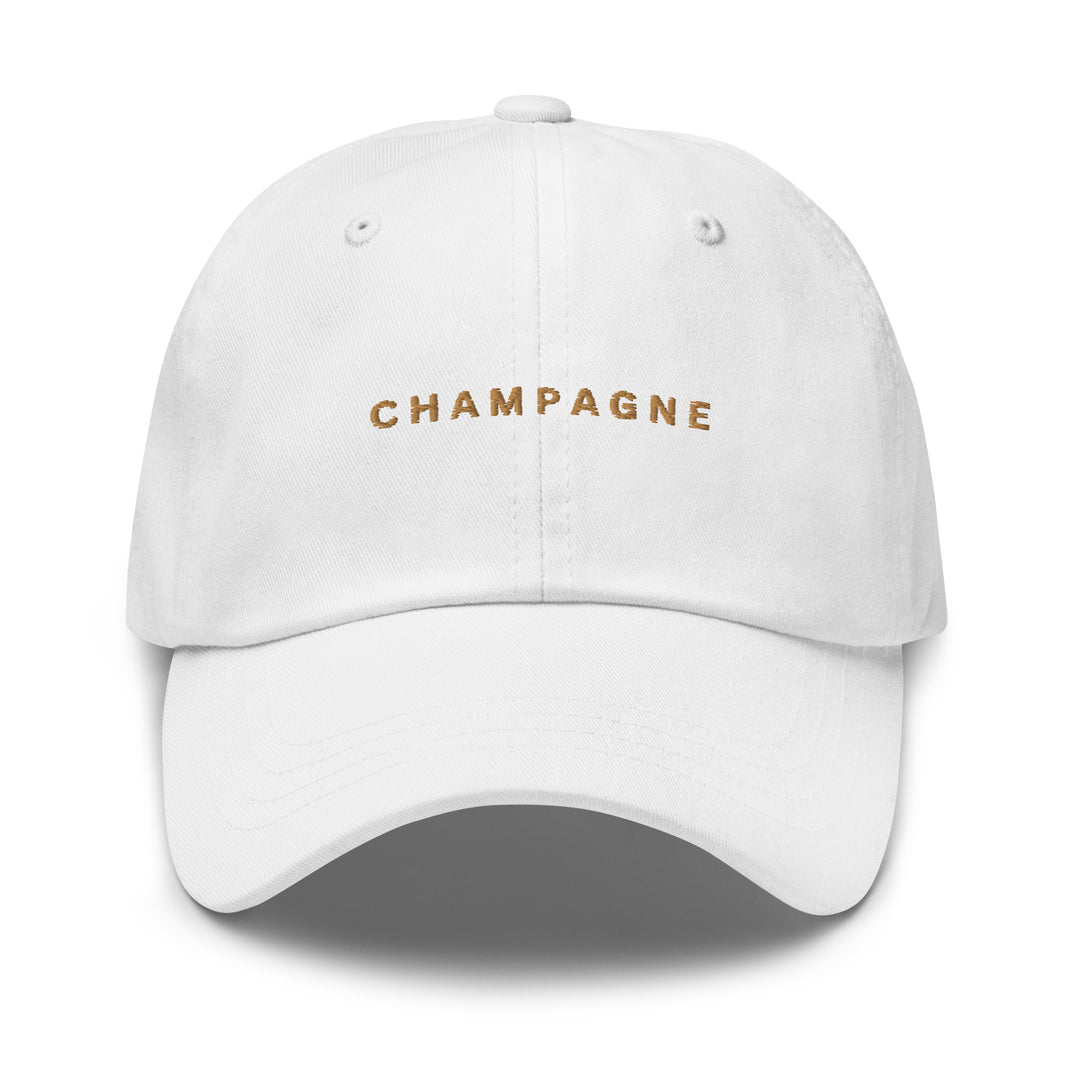 The Champagne Dad Hat by Tequila & Sunrise showcases the word CHAMPAGNE beautifully embroidered in gold on the front. Crafted from chino cotton twill, this white hat combines comfort and style, featuring an adjustable strap for a perfect fit.