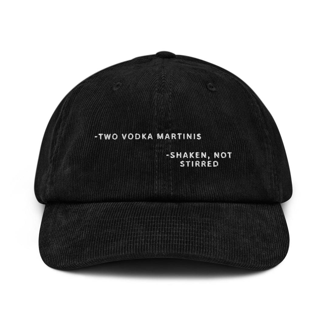 Introducing "The Shaken, not Stirred James Bond Quote Corduroy Hat" by Tequila & Sunrise—an elegant black hat crafted from cotton corduroy. It features the iconic text "-TWO VODKA MARTINIS -SHAKEN, NOT STIRRED" embroidered in white on the front. With its adjustable buckle, this cap effortlessly combines style and comfort for a perfect fit.