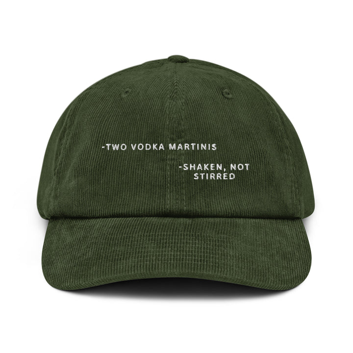 Introducing The Shaken, not Stirred James Bond Quote Corduroy Hat by Tequila & Sunrise: This dark green cotton corduroy baseball cap features the phrase "Two Vodka Martinis - Shaken, Not Stirred" embroidered in white on the front. It comes with an adjustable buckle to ensure a comfortable fit.