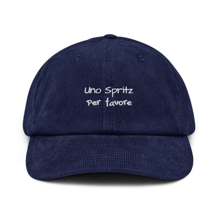 The Uno Spritz Per Favore Corduroy hat by Tequila & Sunrise is a navy blue corduroy accessory featuring the phrase embroidered in white on the front. Crafted from premium cotton corduroy, it includes an adjustable buckle for a customized fit.