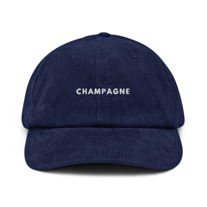 Introducing The Champagne Corduroy hat by Tequila & Sunrise: a navy blue cotton corduroy cap with "CHAMPAGNE" elegantly embroidered in white on the front, complete with an adjustable buckle for the perfect fit.