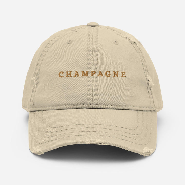 The Champagne Hat by Tequila & Sunrise is a beige dad hat with slight distressing that features an elegant Champagne design. The word "CHAMPAGNE" is beautifully embroidered on the front in gold lettering, making it a perfect accessory to add sophistication to any wardrobe.