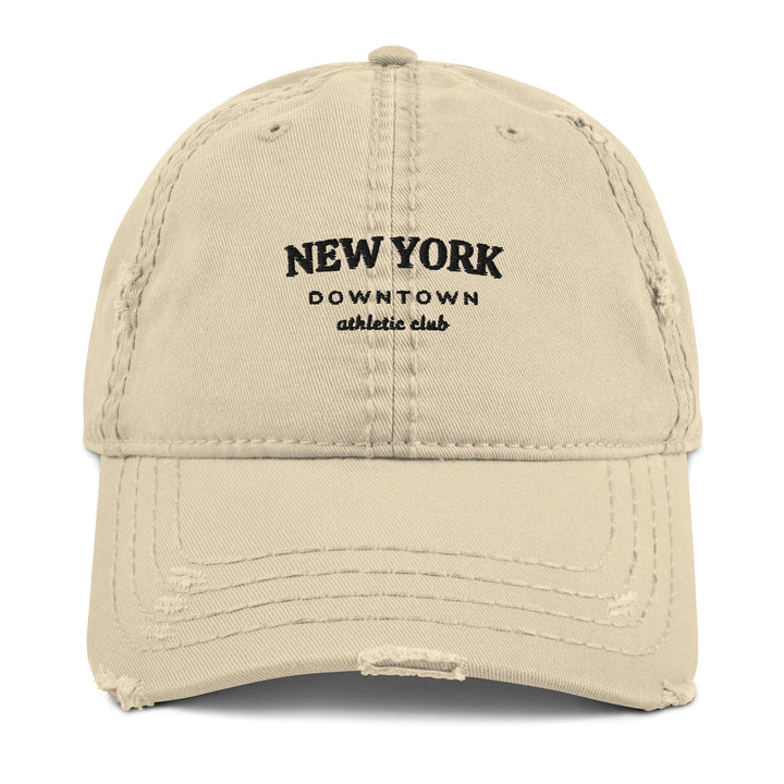 The New York Downtown Athletic Club Hat by Tequila & Sunrise is a beige dad hat made from pre-shrunk cotton twill, featuring the club's name in black on the front and a stylishly distressed brim.