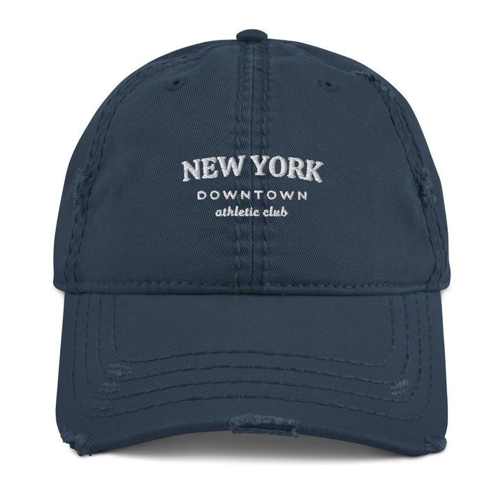 The New York Downtown Athletic Club Hat by Tequila & Sunrise is a navy blue dad hat with a distressed brim, featuring the text "New York Downtown Athletic Club" elegantly embroidered in white. It is crafted from pre-shrunk cotton twill for a comfortable fit.