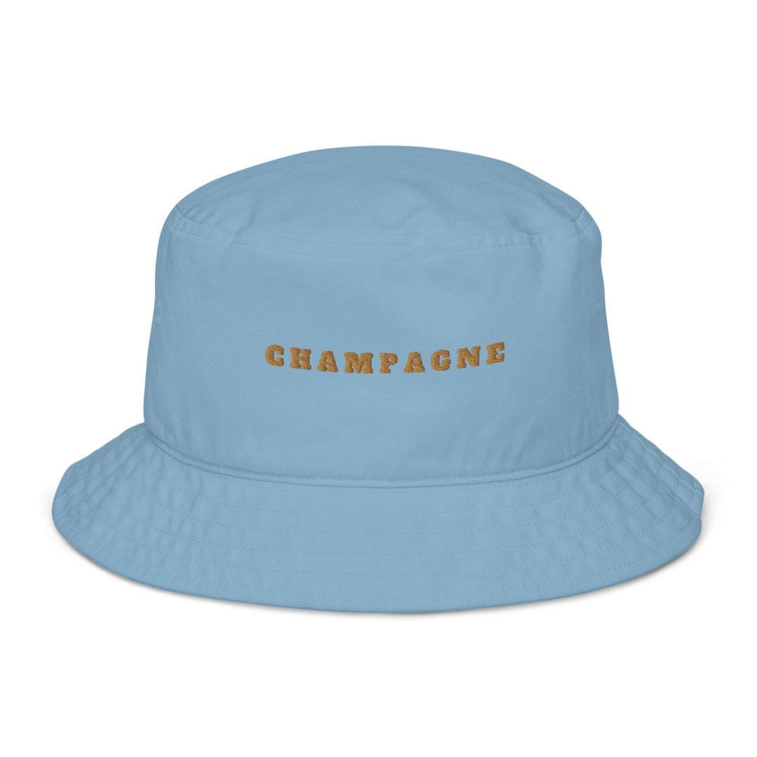 The Champagne Organic Bucket Hat by Tequila & Sunrise is a light blue accessory crafted from 100% eco-friendly cotton, featuring "CHAMPAGNE" embroidered in gold across the front.