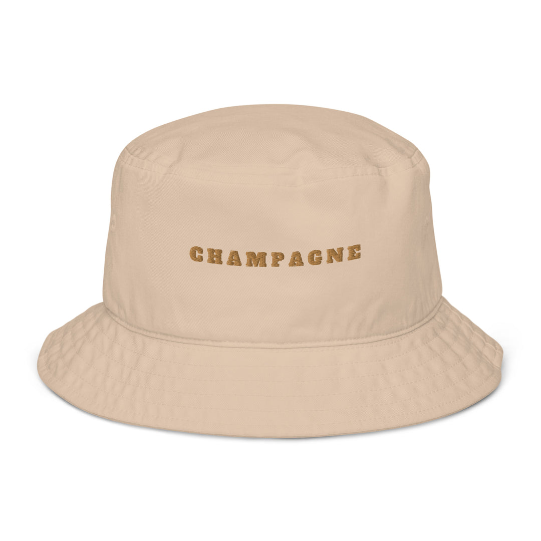 The Champagne Organic Bucket Hat by Tequila & Sunrise is an eco-friendly beige bucket hat made from 100% cotton, with "CHAMPAGNE" elegantly embroidered in gold on the front.