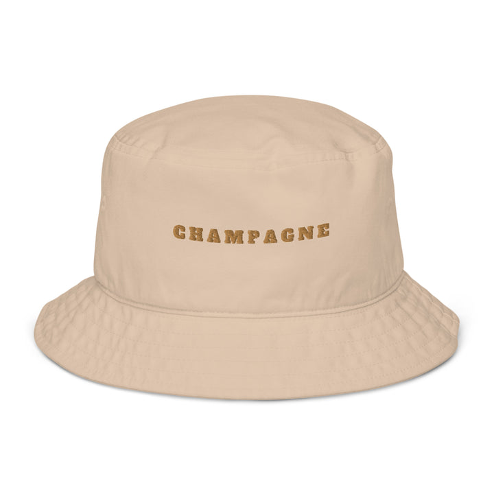 The Champagne Organic Bucket Hat by Tequila & Sunrise is an eco-friendly beige bucket hat made from 100% cotton, with "CHAMPAGNE" elegantly embroidered in gold on the front.