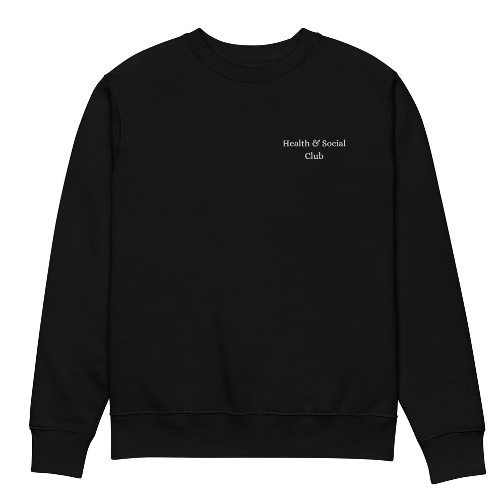 The Tequila & Sunrise "The Health & Social Club Eco Sweatshirt" is a black crew neck made on demand. It showcases the phrase "Health & Social Club" in small white text on the left chest and is crafted from durable and comfy organic cotton, maintaining a plain appearance without additional designs or patterns.