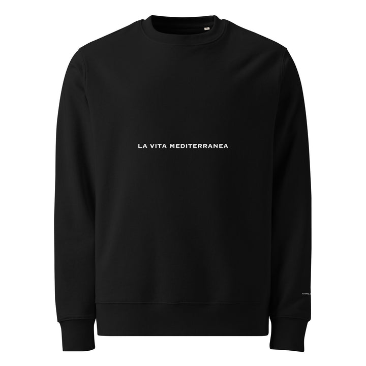 Introducing *The La Vita Mediterranea Eco Sweatshirt* by Tequila & Sunrise: a cozy black sweatshirt made from organic cotton. It features the text "La Vita Mediterranea" in white prominently displayed on the front. Its simple and minimalistic design perfectly captures the Mediterranean lifestyle, while its long sleeves and rounded neckline offer both comfort and style.