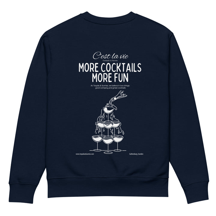 The More Cocktails More Fun Eco Sweatshirt by Tequila & Sunrise highlights a graphic of a champagne fountain with glasses and a bottle. It includes the text “C'est la vie, more cocktails more fun” and celebrates good company, all made from organic cotton for fans of sustainable fashion.