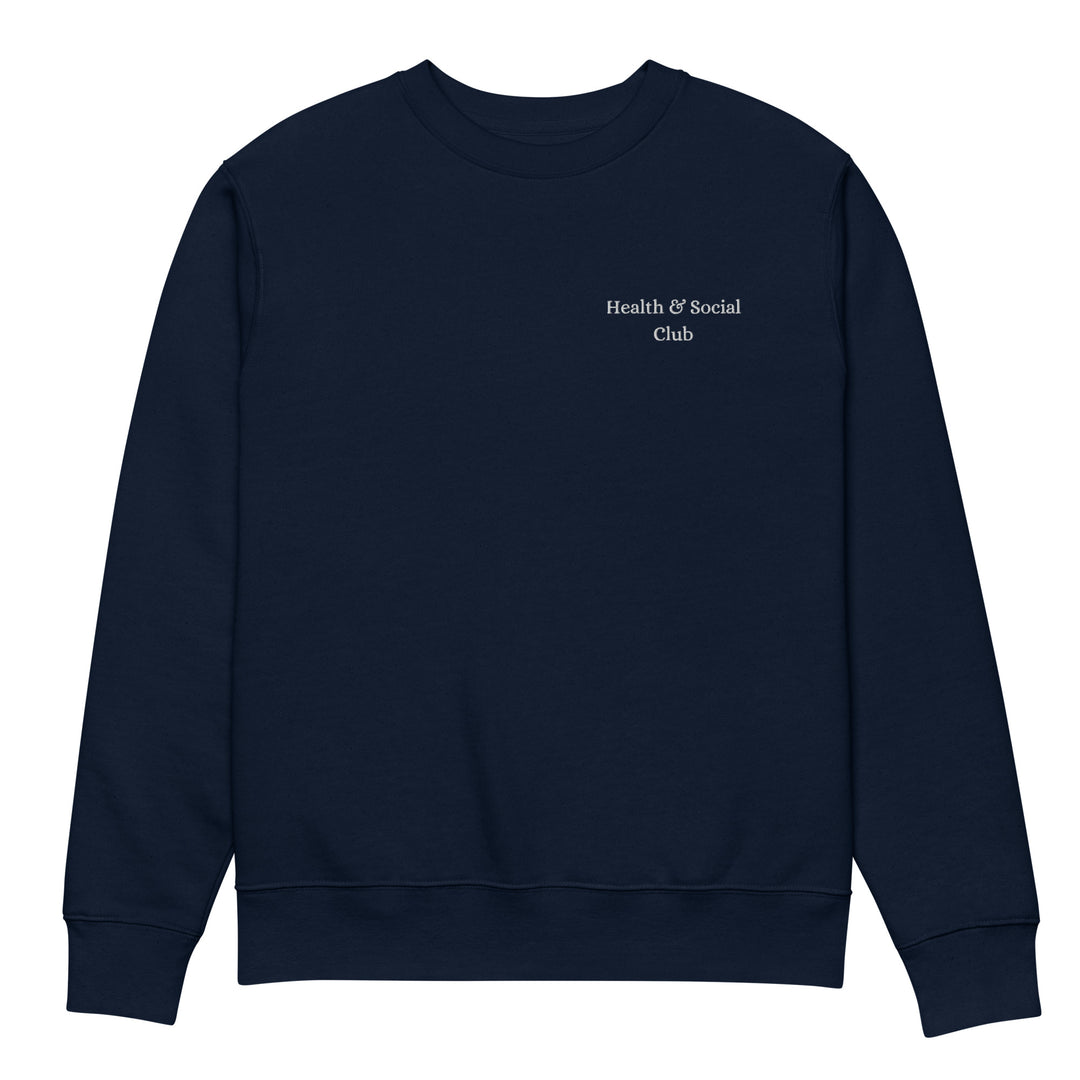 Introducing The Health & Social Club Eco Sweatshirt by Tequila & Sunrise: Crafted from organic cotton, this navy blue sweatshirt boasts the phrase "Health & Social Club" in subtle white lettering on the upper left chest. Made on demand for sustainability, it offers a straightforward and minimalist aesthetic that guarantees comfort and durability without any additional graphics or embellishments.