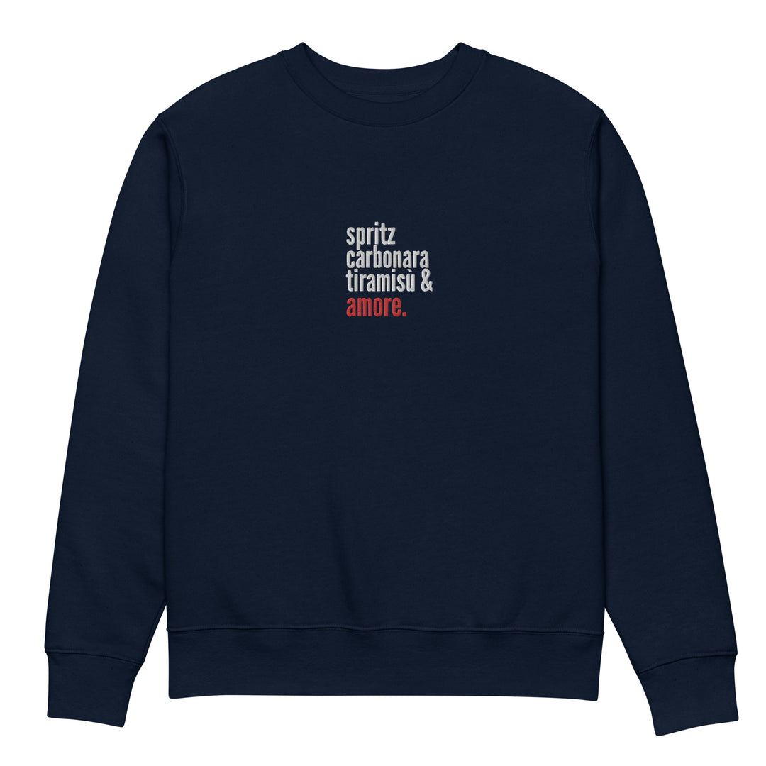 Introducing "The Love from Italy Eco Sweatshirt" by Tequila & Sunrise: this stylish navy blue sweatshirt, made from organic cotton, showcases the words "spritz," "carbonara," and "tiramisu" in crisp white text with "amore." elegantly highlighted in red. The words are aligned vertically, capturing Italian flair against a clean white backdrop.