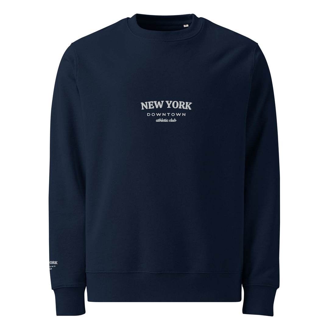 The navy blue sweatshirt, known as "The New York Downtown Athletic Club Eco Sweatshirt" by Tequila & Sunrise, is made from organic cotton and showcases the text "NEW YORK DOWNTOWN ATHLETIC CLUB" embroidered in white on the chest. This durable piece features long sleeves and a simple, classic design.