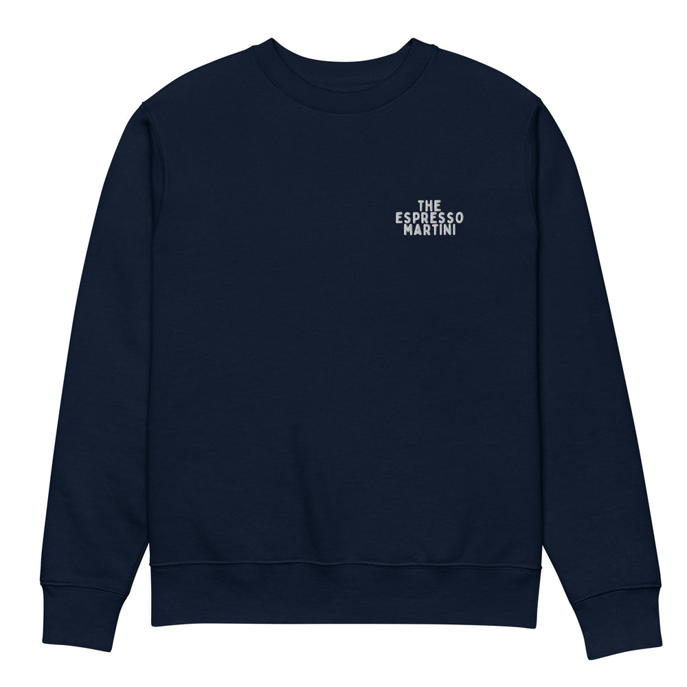 The Espresso Martini Eco Sweatshirt by Tequila & Sunrise is a navy blue garment made from organic cotton, adorned with the phrase "Espresso Martini" in small white letters on the upper left chest. Its design is simple and minimalistic, providing a stylish and durable addition to your wardrobe.