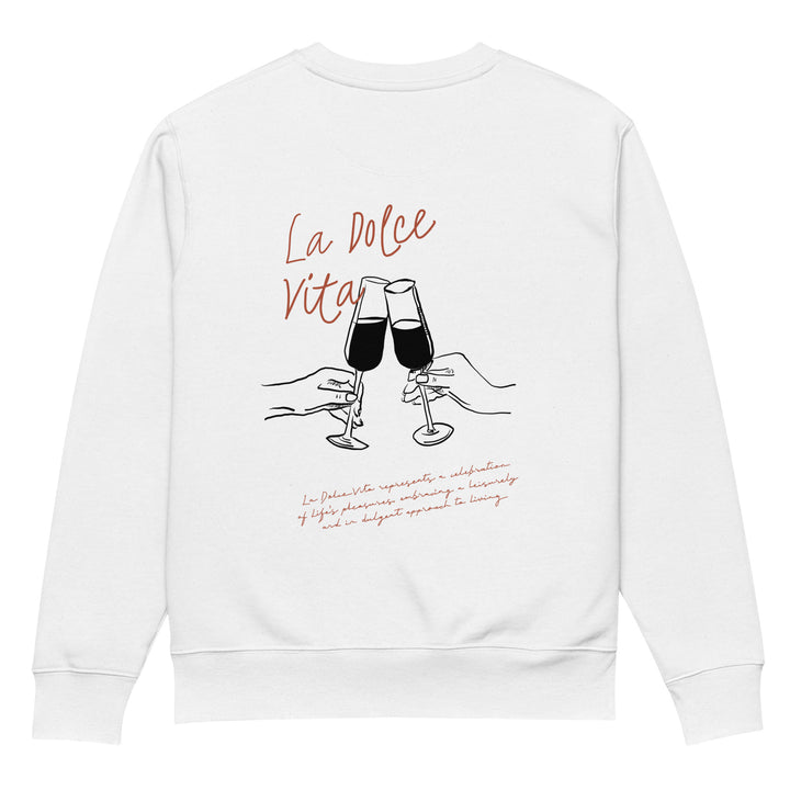 Introducing The La Dolce Vita Eco Sweatshirt by Tequila & Sunrise: This organic cotton sweatshirt showcases an embroidered illustration of two hands clinking wine glasses. Above this charming image, "La Dolce Vita" is beautifully inscribed in cursive. Beneath it, a paragraph of small red text adds intrigue as part of the design. Each sweatshirt is made on demand, ensuring every piece offers a truly unique wear experience.