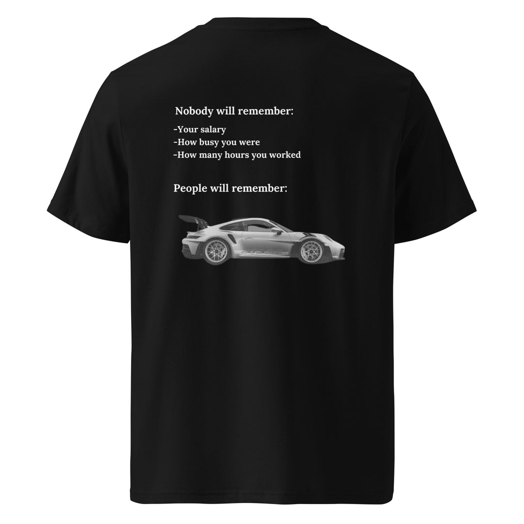 Introducing the Tequila & Sunrise "The Porsche Nobody Will Remember You" Organic T-shirt: a unisex black tee that showcases a stylish sports car image and thought-provoking text about life's memorable and forgettable moments, such as salary and work hours. Crafted from eco-friendly, organic cotton, it offers both comfort and sustainability.