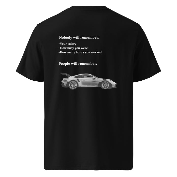 Introducing the Tequila & Sunrise "The Porsche Nobody Will Remember You" Organic T-shirt: a unisex black tee that showcases a stylish sports car image and thought-provoking text about life's memorable and forgettable moments, such as salary and work hours. Crafted from eco-friendly, organic cotton, it offers both comfort and sustainability.