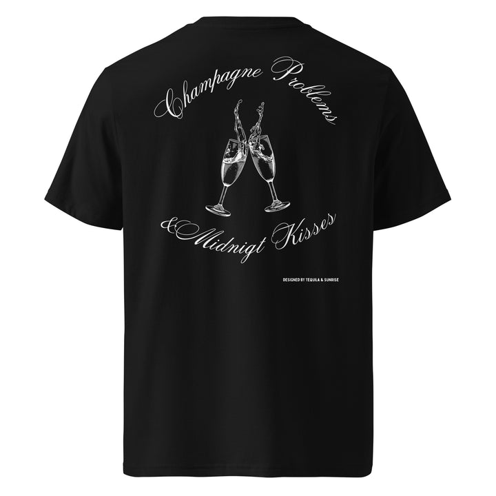 Champagne Problems & Midnight Kisses Organic T-shirt featuring two champagne glasses illustration on a black background.