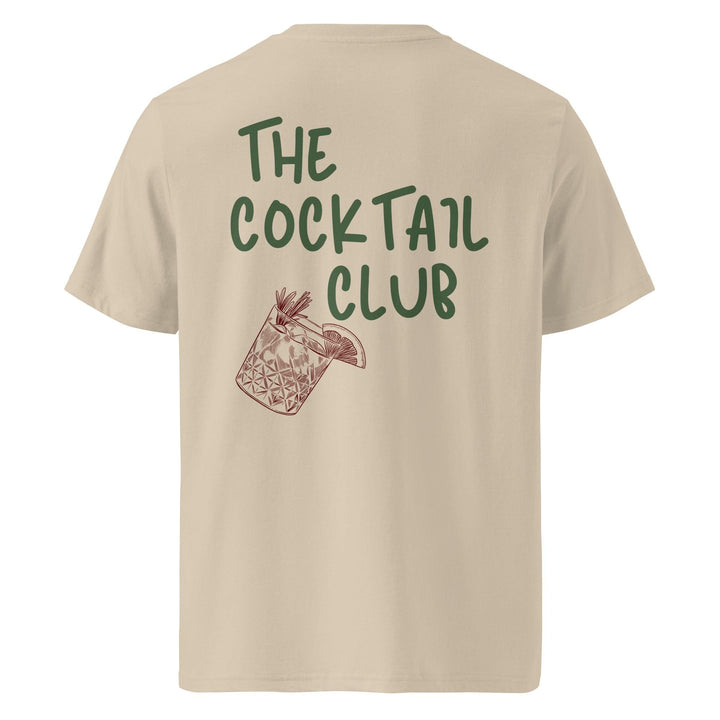 The Tequila & Sunrise "The Cocktail Club Organic T-shirt" offers a sustainable choice with its beige design made from organic cotton. It showcases green text that reads "The Cocktail Club," accompanied by a brown cocktail glass illustration with a garnish, making it an ideal selection for any casual outing.