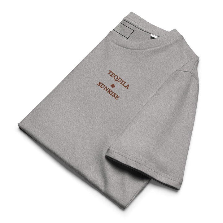 This eco-friendly folded T-shirt from Tequila & Sunrise is crafted from organic cotton in gray and features "The Tequila & Sunrise Organic T-shirt" graphic printed in brown on the chest.