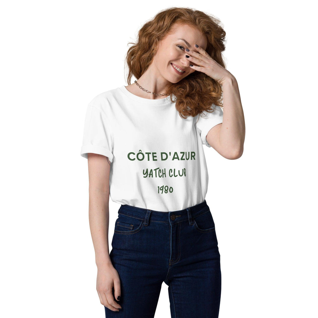 A person with long, curly hair is wearing a Côte d'Azur Yacht Club Organic T-shirt by Tequila & Sunrise, covering part of their face with one hand and standing against a white background, capturing the breezy elegance of the French Riviera.