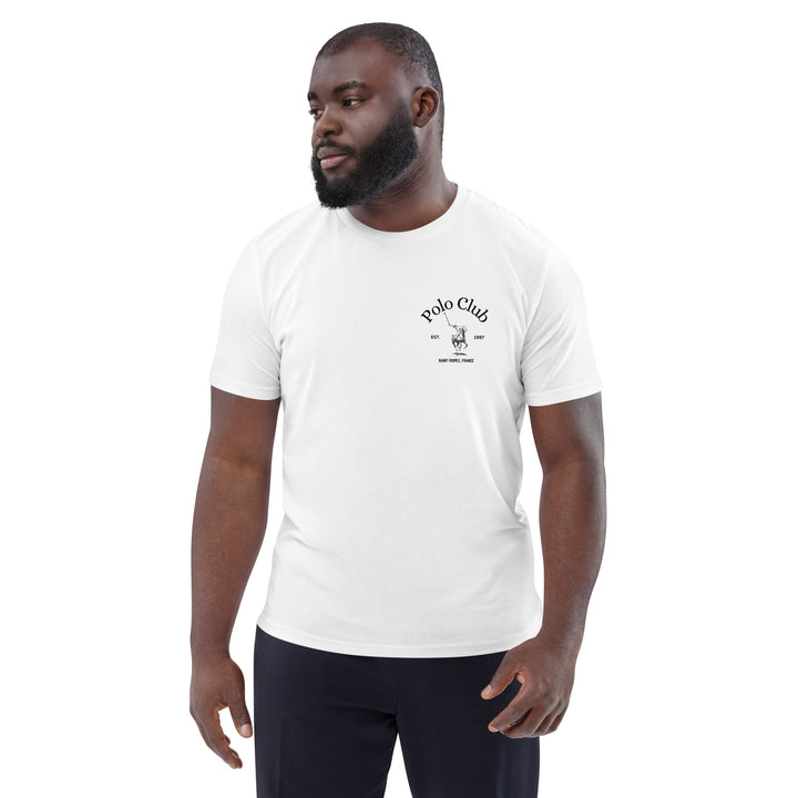 A man with a beard is wearing a white The St-Tropez Polo Club Organic T-shirt by Tequila & Sunrise and black pants, standing against a plain background.